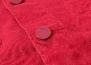 Detailed macro shot of red denim fabric texture and tone-on-tone engraved jeans button