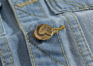 Macro shot of vintage bronze button with fashion text on distressed blue denim vest