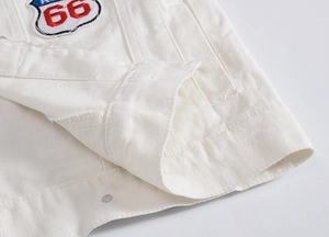Close-up detail of white denim vest featuring retro 66 embroidery and twill fabric texture