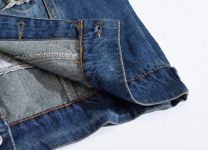 Macro view of blue denim vest edge with orange contrast stitching and buttonhole detail