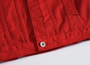 Dettaglio macro dell'orlo della giacca di jeans rossa con cuciture e bottone in metallo
