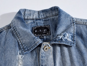 Detailed macro view of light blue denim vest showing collar and metal buttons