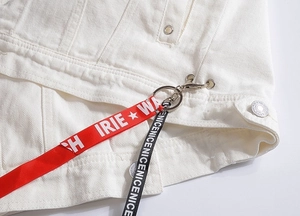 Detailansicht der weißen Jeansweste mit rot-schwarzen Logo-Bändern und Metall-Karabinerhaken