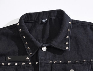 Close-up of black denim biker vest with silver punk metal studs and metallic buttons