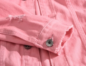 Close-up of pink denim jacket featuring distressed ripped details and metal buttons