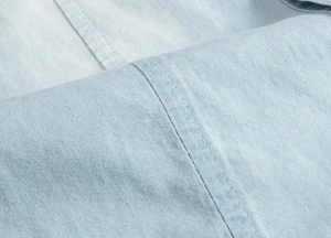 Close-up of light blue denim fabric texture and detailed double-stitched sewing finish