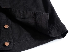 Detail of black denim vest with bronze buttons and double-stitched seams and textures