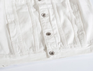 Dettaglio di una giacca di jeans in cotone bianco con twill denso e bottoni in metallo argento