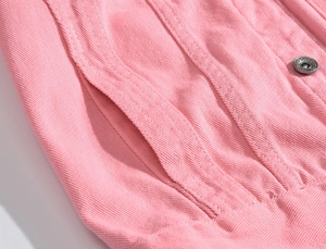 Dettaglio della giacca di jeans rosa con bottone in metallo argentato e cuciture della tasca