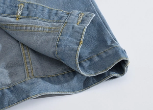 Close-up of light blue denim vest hem with detailed yellow stitching and twill texture