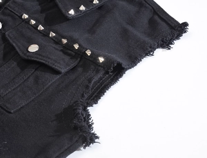 Macro detail of black denim vest featuring silver punk rivets and raw edge craftsmanship