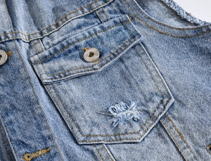 Close-up of distressed blue denim vest with flap pocket and yellow contrast stitching