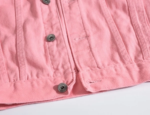 Dettaglio giacca di jeans rosa con bottoni in metallo vintage e cuciture bianche