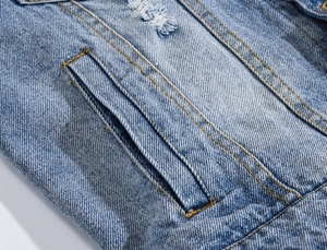 Detailed macro shot of light blue denim vest with contrast stitching and worn texture