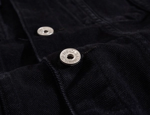 Dettaglio dei bottoni in metallo argento vintage su una giacca di jeans nera in primo piano