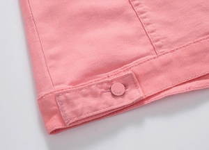 Detailed close-up of pink denim jacket hem featuring double stitching and jeans button