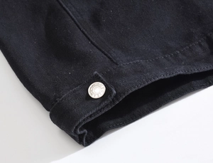 Close-up of silver metal jeans button with star detail on black denim vest hem