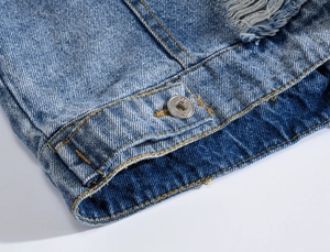 Close-up of light blue denim vest with silver NYC metal button and distressed details