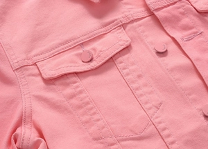 Detailed close-up of pink denim jacket featuring chest pocket and engraved jeans button