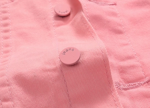 Macro shot of pink denim fabric texture with engraved buttons on the jacket sleeve