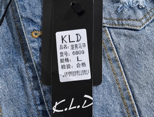 Detail of light blue denim vest with yellow contrast stitching and frayed shoulder seams