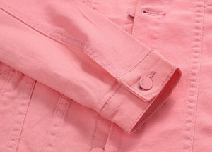 Close-up of pink denim jacket sleeve showing button detail and quality twill fabric