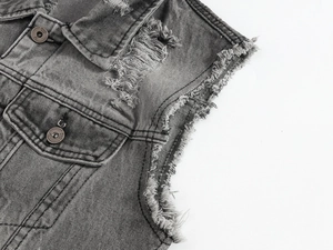 Dettaglio del gilet in denim grigio lavato con strappi pesanti e bordi sfrangiati