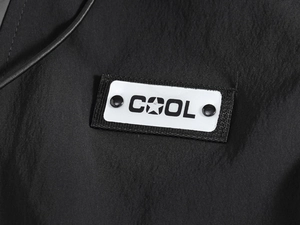 Macro shot of techwear vest fabric with a COOL badge and star motif on black material