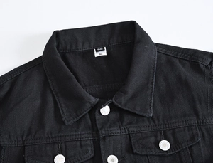 Dettaglio del colletto di un gilet in denim nero con etichetta M e bottoni vintage