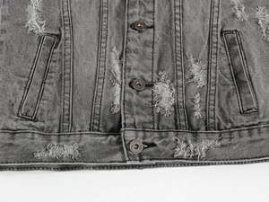 Dettaglio del gilet in denim grigio con texture strappata e bottoni metallici