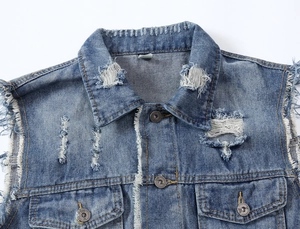 Close-up of blue denim vest featuring distressed holes, raw edges, and vintage metal buttons