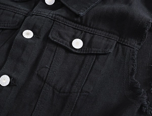Dettaglio del gilet in denim nero con bottoni metallici e bordi sfrangiati alla moda