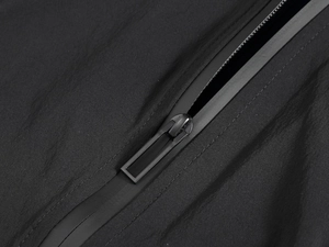 Detailed macro view of the waterproof taped zipper on black functional outdoor vest fabric