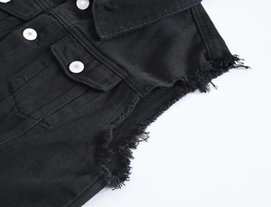 Dettaglio del gilet di jeans nero che mostra bottoni metallici e orlo a taglio vivo