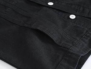 Dettaglio macro del gilet in denim nero con bottoni metallici e cuciture di qualità