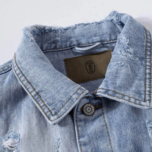 Close-up of distressed denim vest collar with frayed edges and classic fashion button