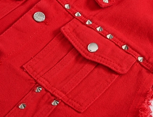 Detail of red denim vest featuring silver conical metal studs and frayed edges on seams