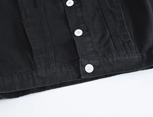 Dettaglio dell'orlo del gilet in denim nero con bottoni in metallo incisi e cuciture rinforzate