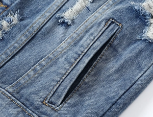 Detail of distressed blue denim vest showing ripped texture and yellow contrast stitching