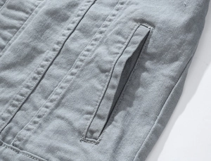 Detail of slanted pocket and precise stitching on gray slim-fit stretch denim jacket