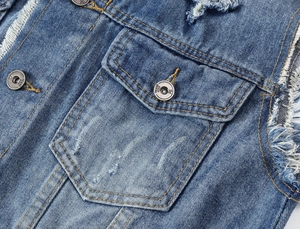 Detailed macro of distressed denim vest with metal buttons and frayed sleeve edges