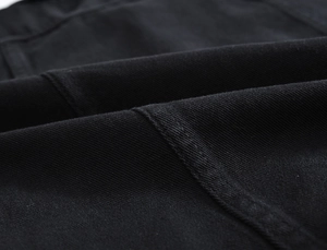 Macro della trama del tessuto denim nero con cuciture di precisione sul gilet