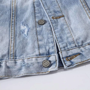 Detailed macro view of distressed light blue denim fabric with classic embossed metal buttons