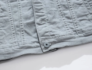 Close-up of light gray denim jacket hem showing double stitching and JEANS button detail
