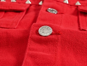 Macro shot of red denim jacket detailing silver rivets and embossed metal jeans buttons