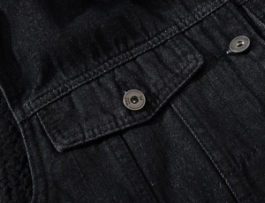 Détail du gilet en jean noir montrant les boutons en métal et la doublure polaire
