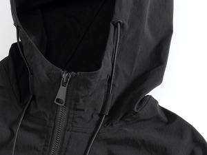 Close-up of black hooded vest featuring a windproof texture and smooth metal zipper