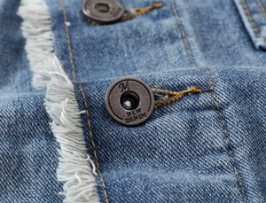 Close-up of vintage denim vest button with frayed edges and yellow stitching details