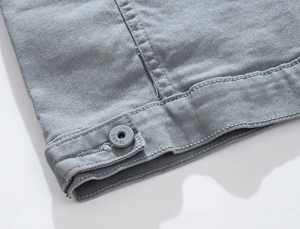 Close-up of grey denim jacket hem with detailed stitching and engraved jeans button