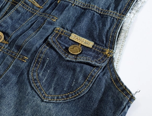 Vue détaillée du tissu denim bleu foncé avec coutures jaunes et plaque logo métallique